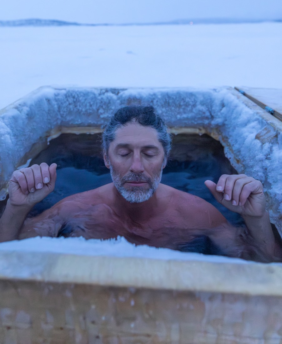 A man with closed eyes sitting calmly in a frost-rimmed plunge tub