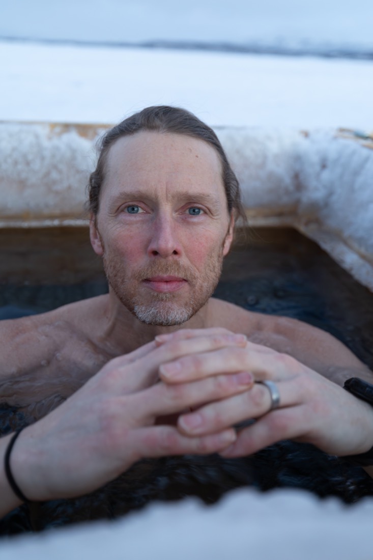 Jonas resting his chin on his hands at the edge of the ice bath