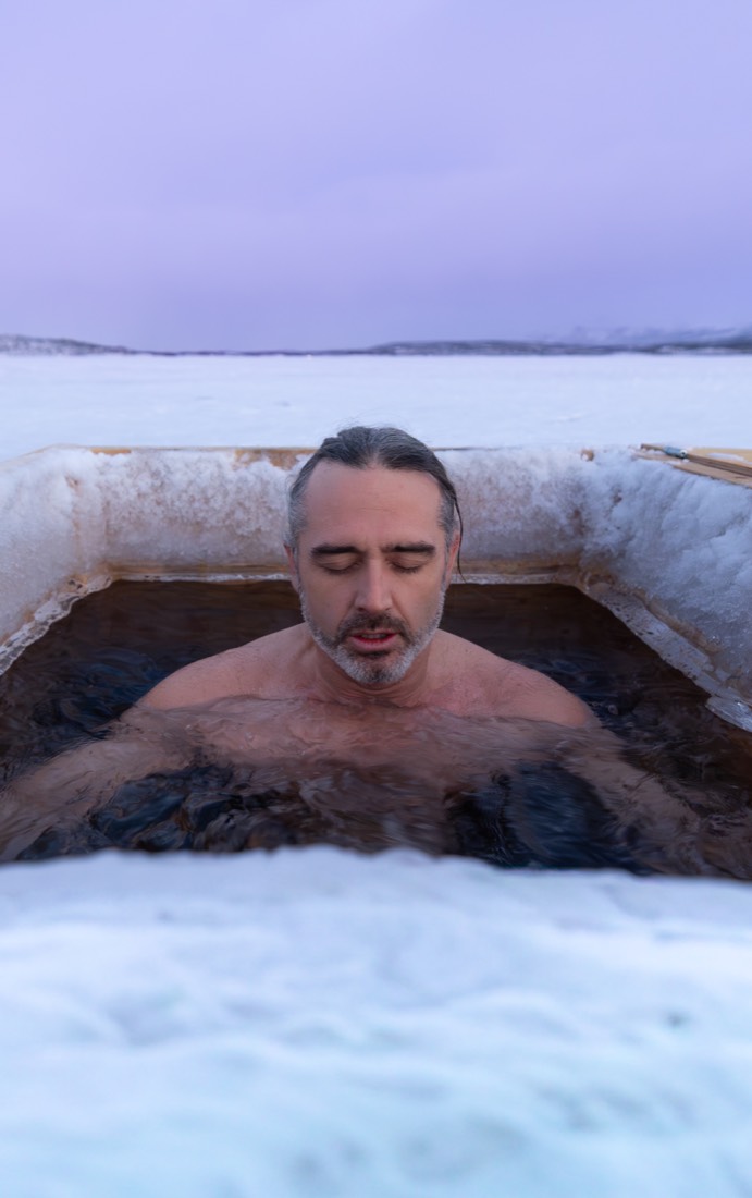 A man in the ice water under a violet Arctic sky