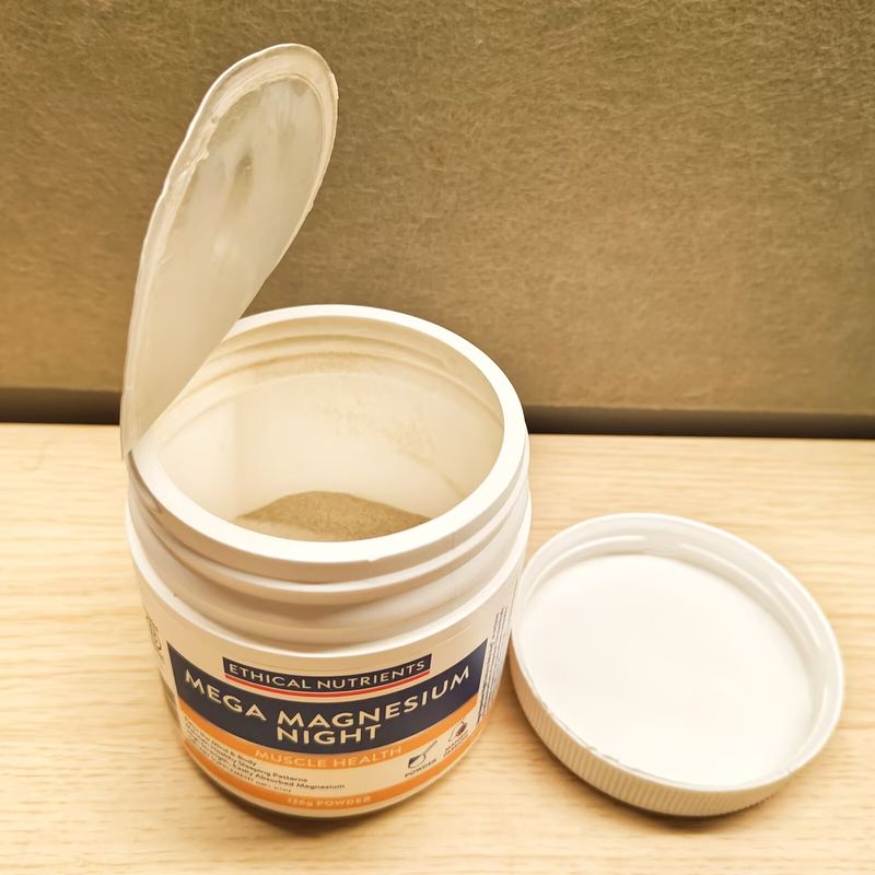 An open tub of magnesium powder and its lid on a wooden table
