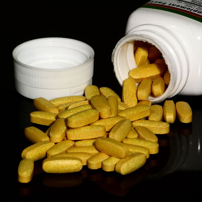 Yellow vitamin tablets spilling from a bottle